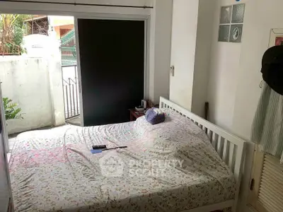 Cozy bedroom with floral bedding and outdoor access, perfect for relaxation.