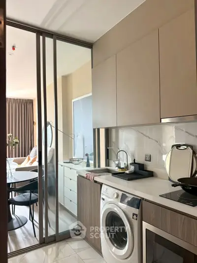 Modern kitchen with washing machine and open layout leading to stylish living area.
