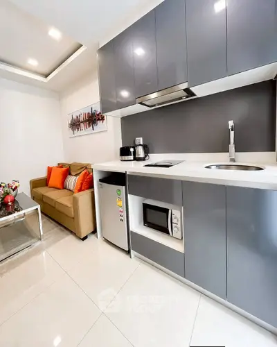 Modern kitchen with sleek cabinets and cozy living area in open layout apartment.