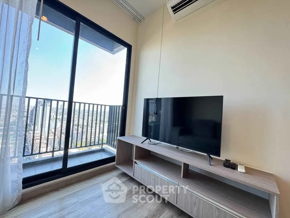 Modern living room with large TV and balcony offering stunning city views.