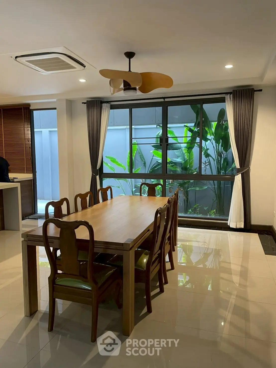 Elegant dining area with wooden table and chairs, large window view, and modern ceiling fan.