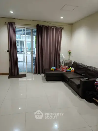 Spacious living room with modern leather sofa and large window for natural light.