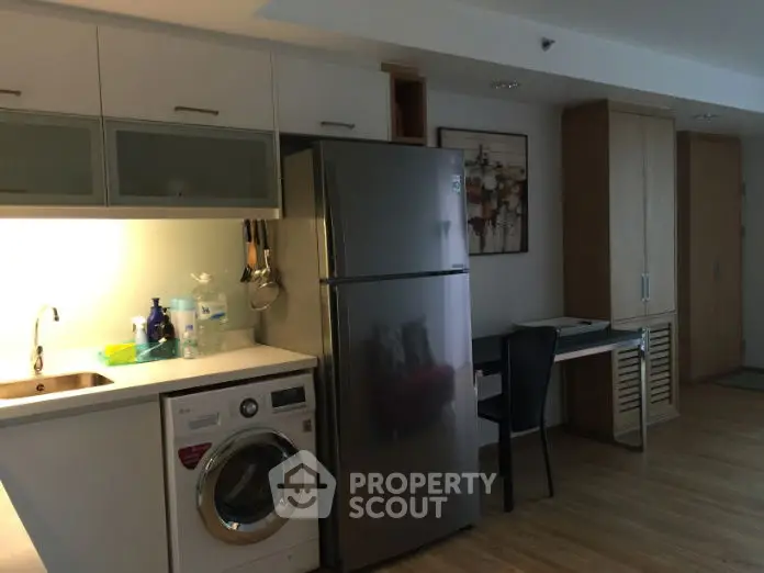 Modern kitchen with stainless steel fridge and washing machine in cozy apartment.