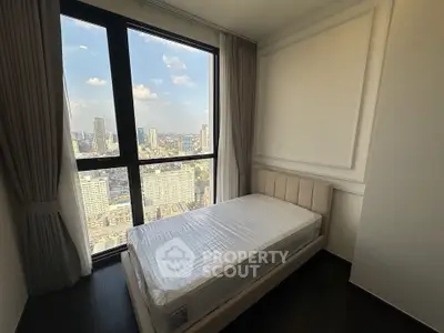 Modern bedroom with stunning city view from large window, featuring a single bed and elegant decor.