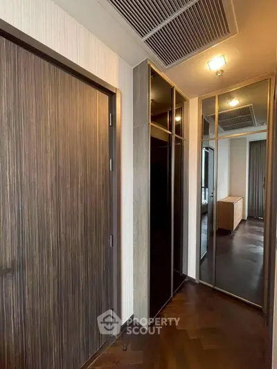 Modern hallway with sleek wooden doors and mirrored closet in upscale apartment.