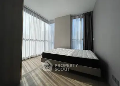 Spacious bedroom with large windows and natural light in modern apartment.