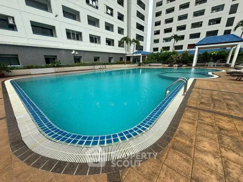 Luxurious apartment complex with stunning outdoor pool and relaxation area.