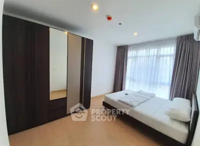 Spacious bedroom with modern wardrobe and large window for natural light.