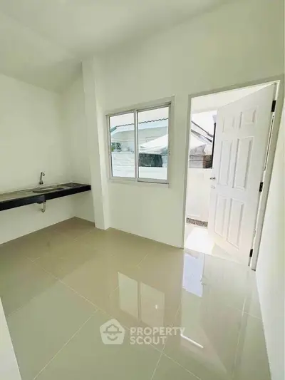 Bright kitchen space with open layout and modern design, featuring a sleek countertop and large window.
