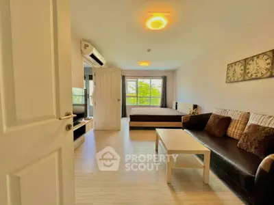 Modern studio apartment with cozy living area and large window view.