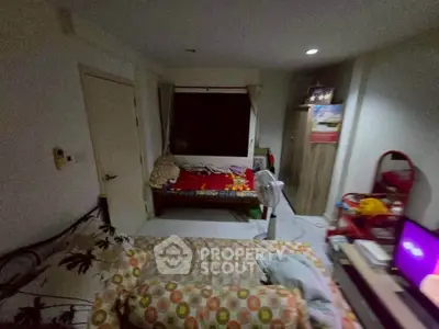 Cozy bedroom with colorful bedding and a window view, featuring a fan and a TV for comfort.