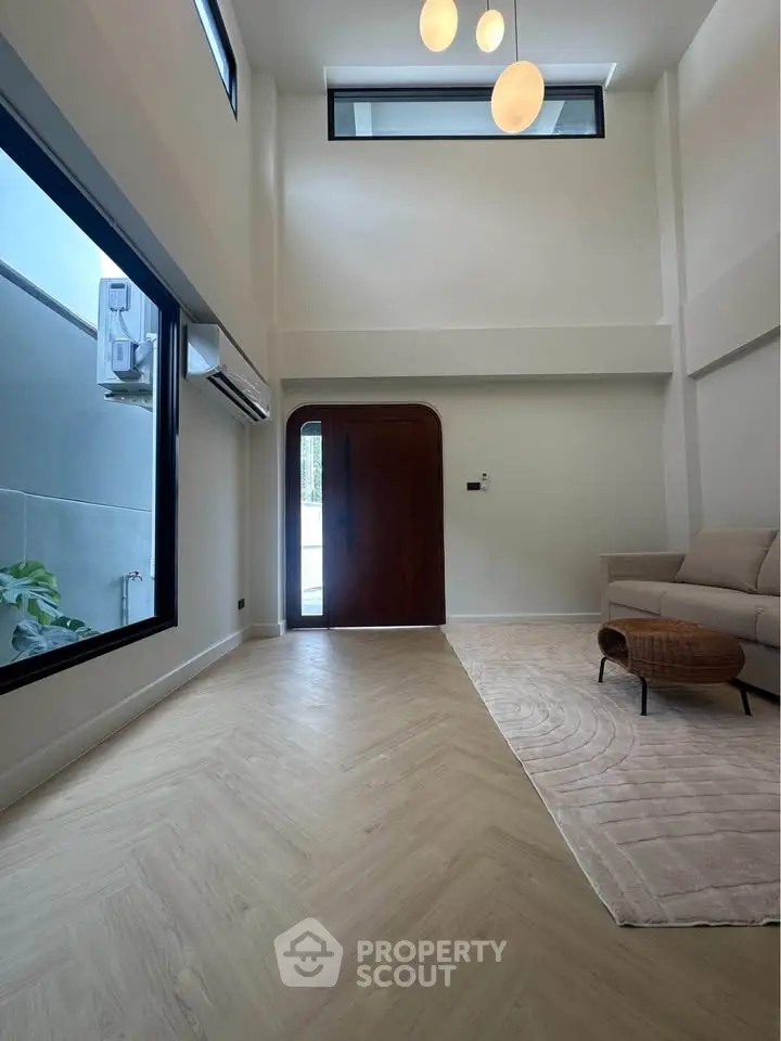 Spacious modern living room with high ceilings and elegant lighting, featuring a cozy seating area and large windows.