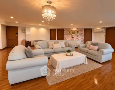 Spacious living room with elegant chandelier and plush sofas in a luxurious apartment.