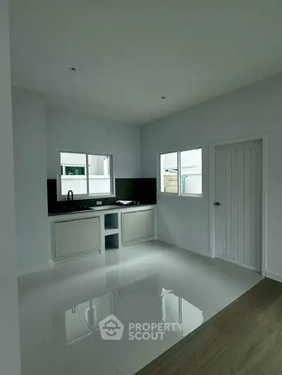 Modern minimalist kitchen with sleek cabinetry and large windows for natural light.