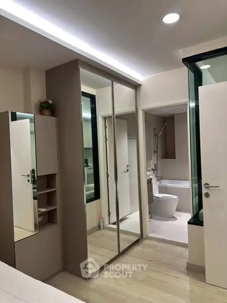 Modern apartment interior with mirrored wardrobe and bathroom view