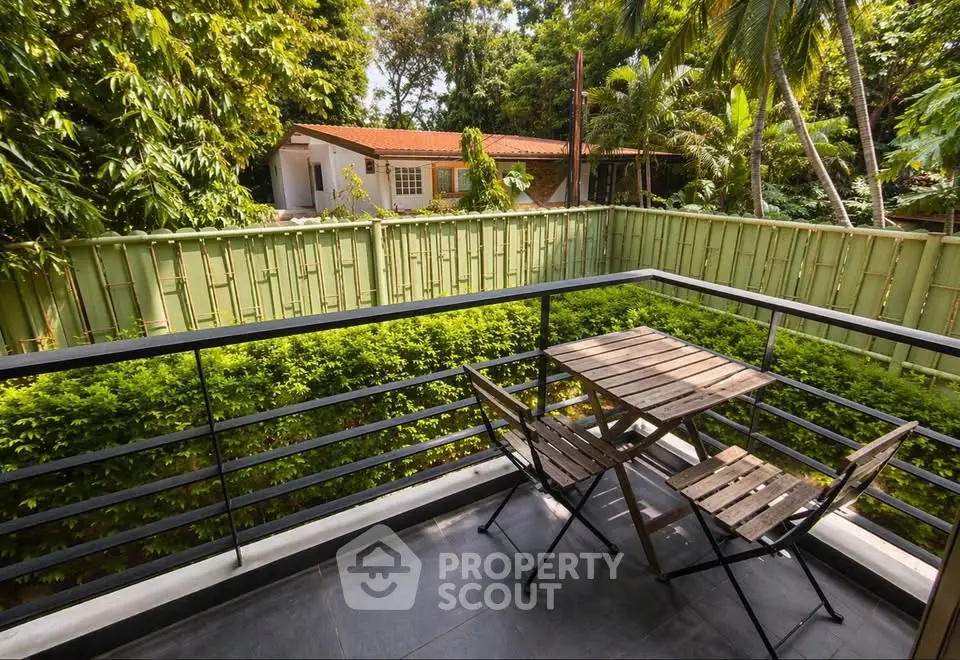 Charming balcony with lush garden view and cozy seating area, perfect for relaxation.