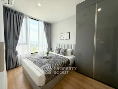 Modern bedroom with city view, featuring sleek grey decor and large windows for natural light.