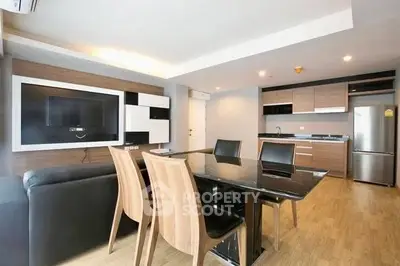 Modern open-plan living room with sleek kitchen and dining area, featuring stylish furniture and contemporary design.