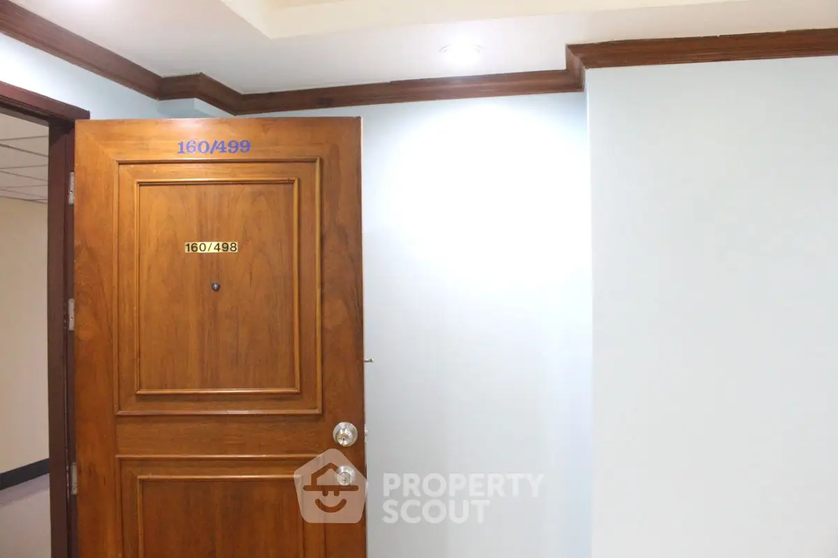 Elegant wooden apartment door with room number, showcasing quality craftsmanship in a modern building.