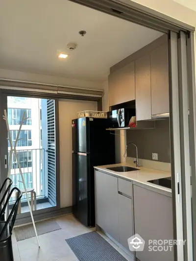 Modern compact kitchen with balcony view in urban apartment