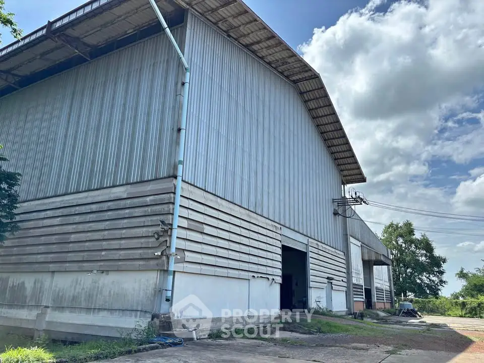 Spacious industrial warehouse with high ceilings and large entry doors, ideal for storage or manufacturing.