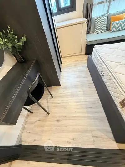 Modern bedroom with stylish decor and wooden flooring, featuring a cozy bed and a compact workspace.