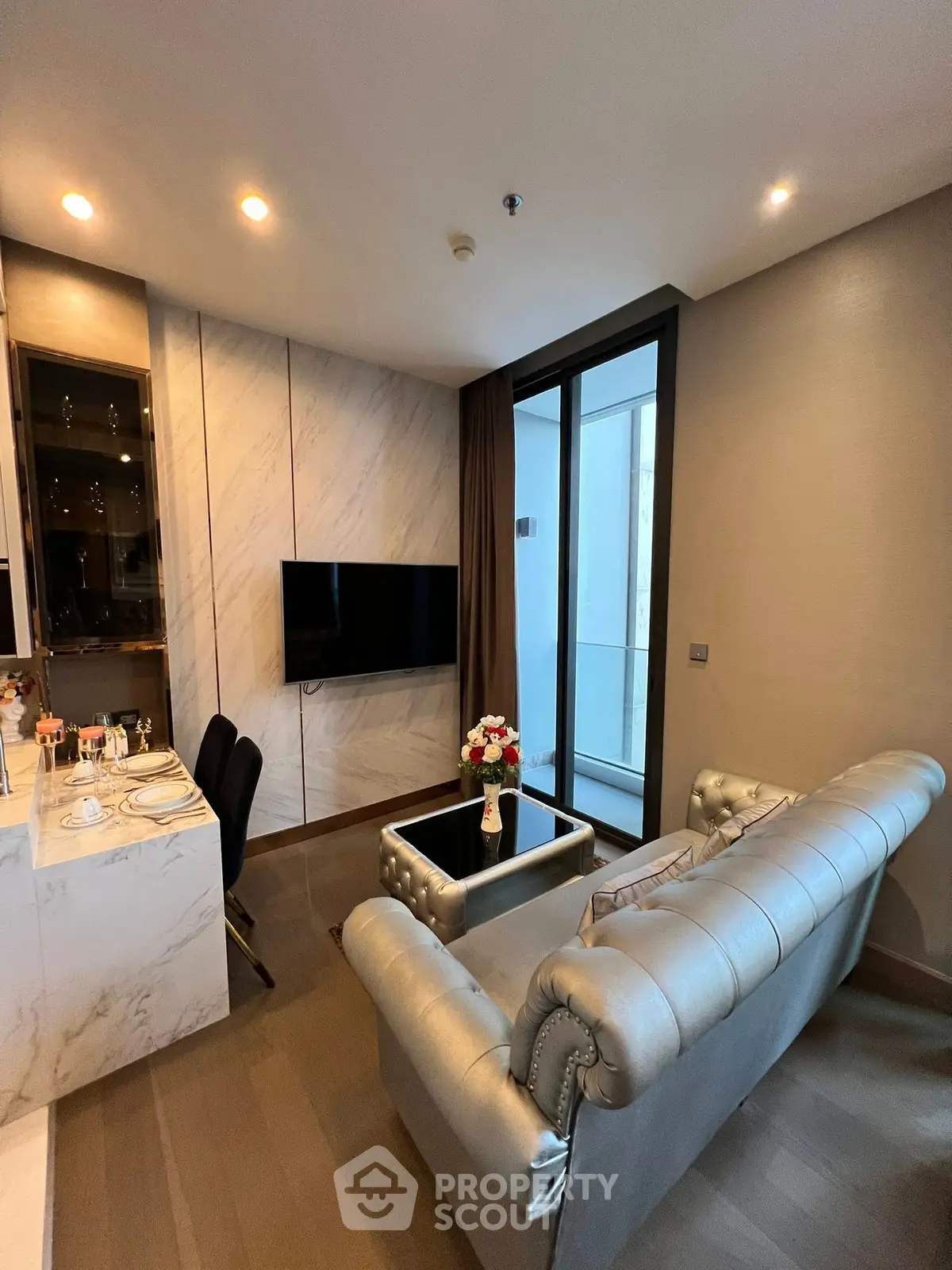 Luxurious living room with elegant sofa and modern decor, featuring a sleek TV and stylish dining area.