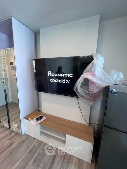 Modern living room with mounted Android TV and sleek wooden console in stylish apartment.