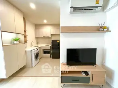 Modern open-layout kitchen and living room with washing machine and TV setup.