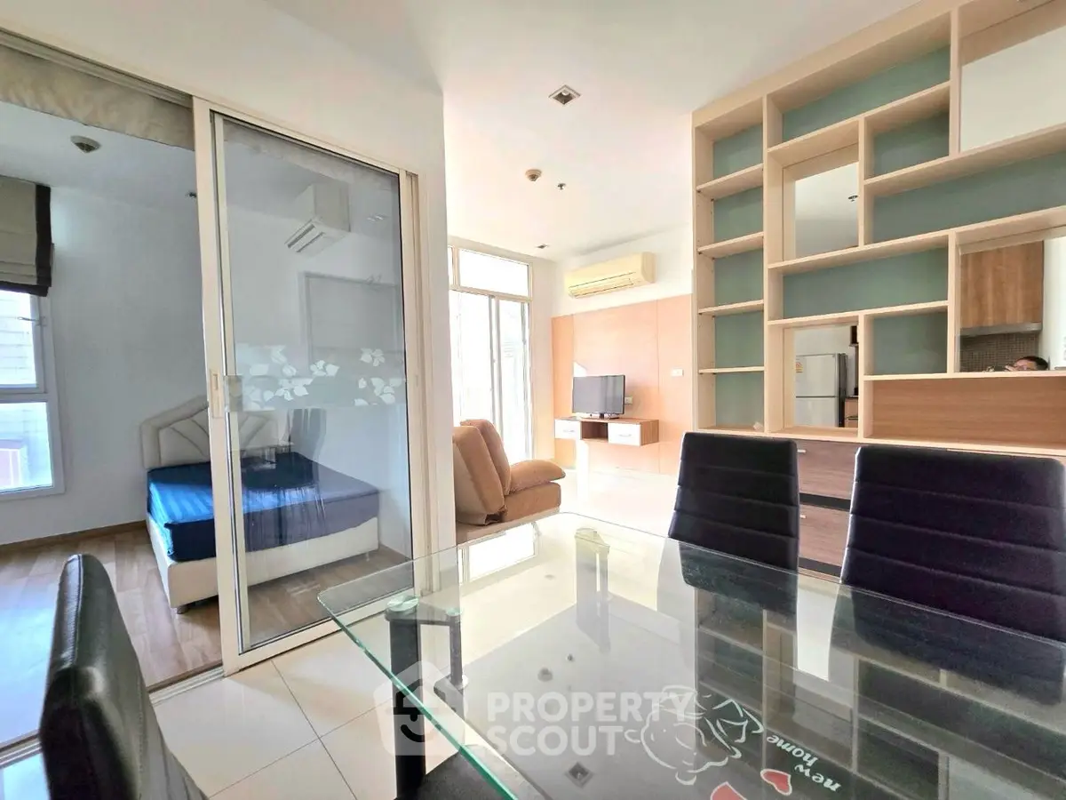 Modern open-plan living room with glass dining table and built-in shelving