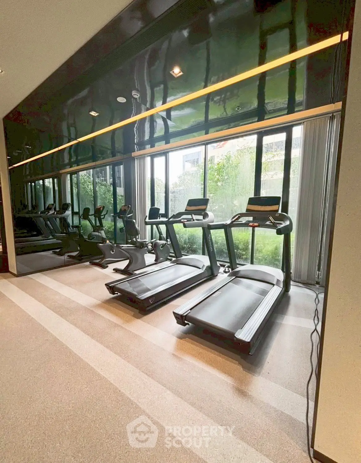 Modern gym with state-of-the-art treadmills and large windows offering garden views.
