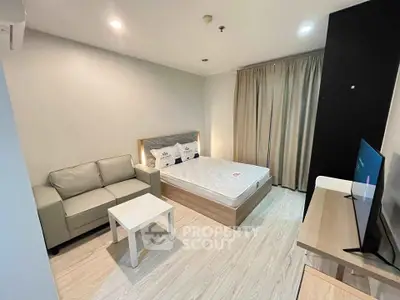 Modern studio apartment with cozy bed, sofa, and TV setup