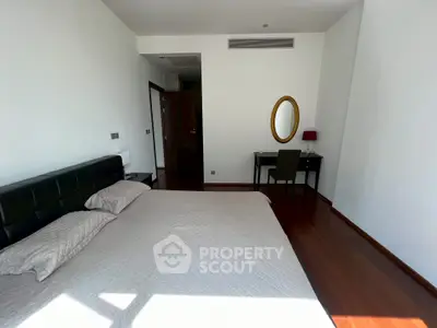Spacious bedroom with elegant decor and natural light, featuring a comfortable bed and stylish desk area.