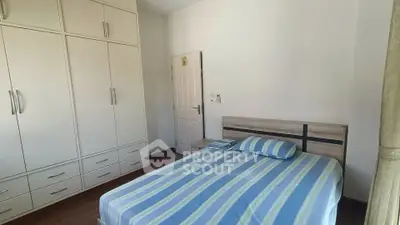 Cozy bedroom with built-in wardrobe and striped bedding in modern apartment.