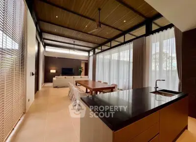 Spacious open-plan living and dining area with modern kitchen and high ceilings.