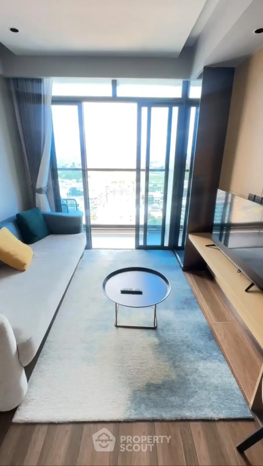 Modern living room with large windows and city view, featuring stylish furniture and decor.