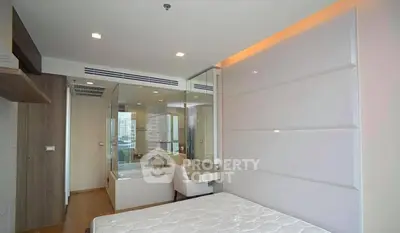 Modern bedroom with glass partition and city view, featuring sleek design and ambient lighting.