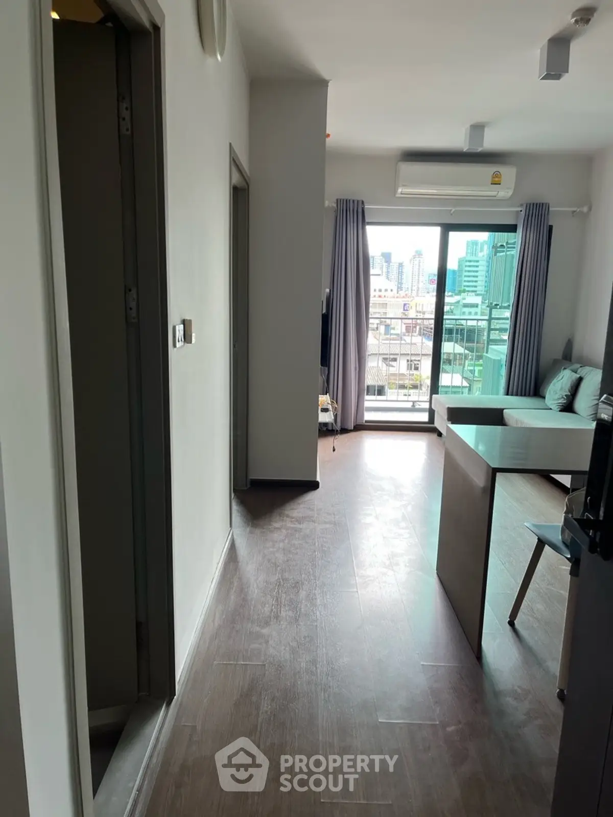 Modern apartment interior with city view from balcony, featuring sleek design and natural light.