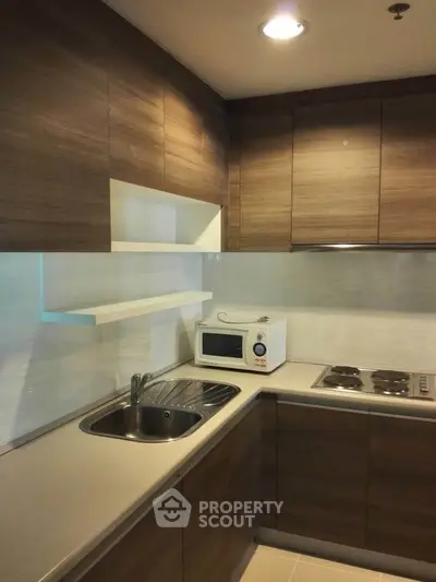 Modern kitchen with sleek wooden cabinets and built-in appliances, featuring a microwave and electric stove.