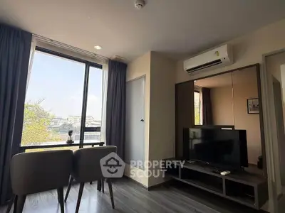 Modern living room with large window and city view, featuring sleek furniture and air conditioning.