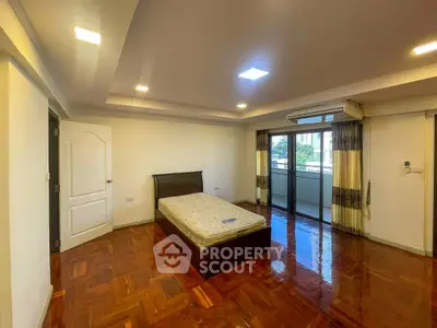 Spacious bedroom with balcony access and polished wooden floors