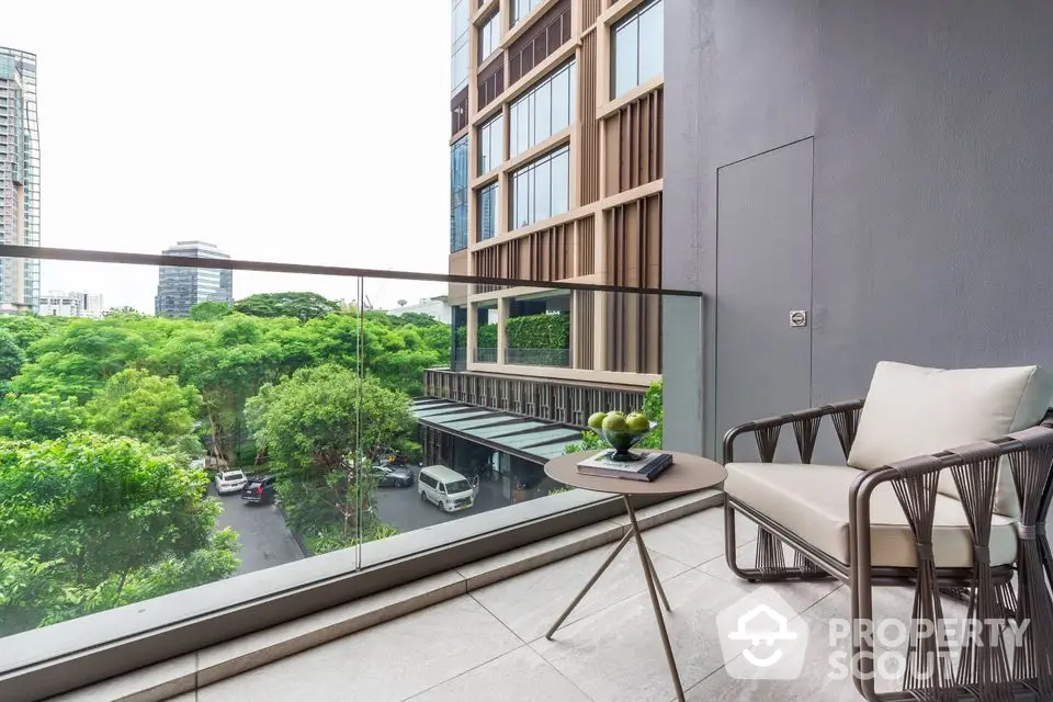 Modern balcony with city view and stylish furniture overlooking lush greenery.