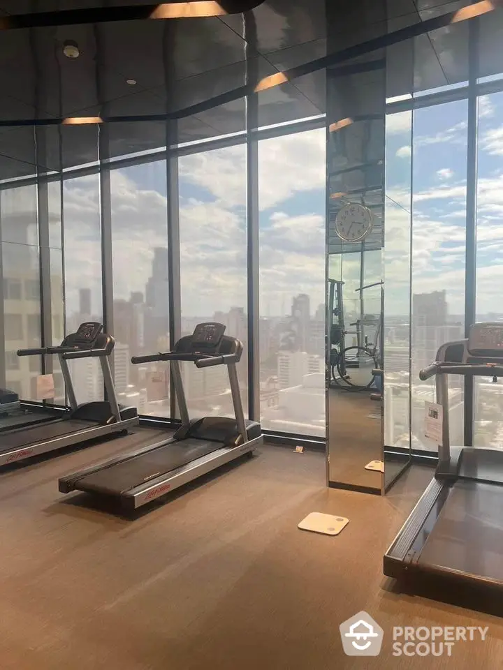 Modern gym with city view and state-of-the-art treadmills in luxury high-rise building.