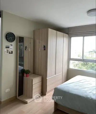 Cozy bedroom with modern wardrobe and large window offering natural light.