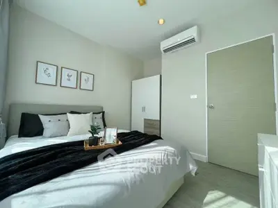 Modern bedroom with stylish decor and natural light, featuring a cozy bed and air conditioning.