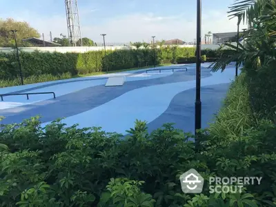 Modern outdoor skate park with lush greenery and blue ramps in a residential area.