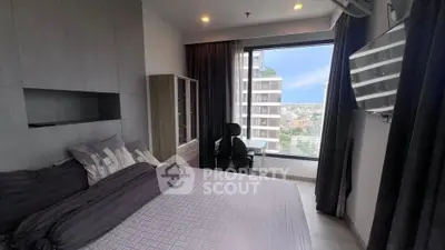Modern bedroom with city view, featuring sleek furniture and large window for natural light.