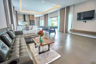 Spacious modern living room with leather sofa, pool table, and open kitchen layout.