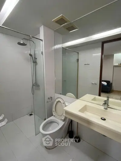 Modern bathroom with glass shower and sleek fixtures in contemporary apartment.