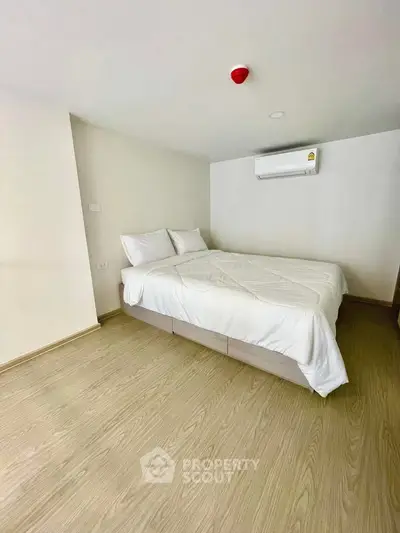 Modern minimalist bedroom with wooden flooring and air conditioning